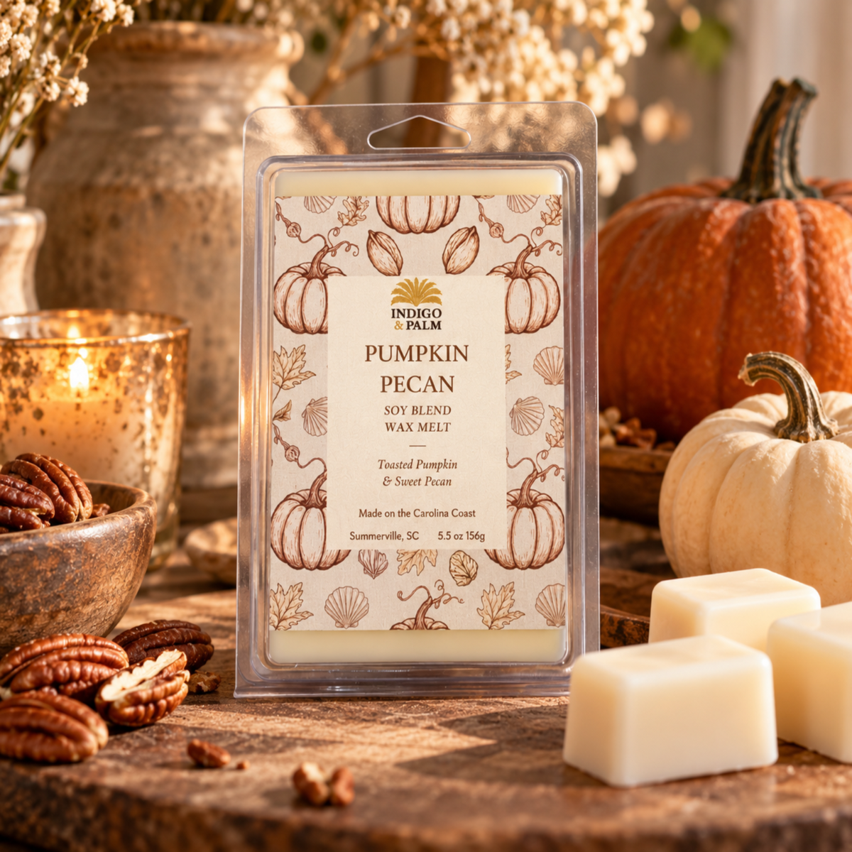 Indigo Palm Pumpkin Pecan scented soy wax melts in a clear plastic clamshell package, styled on a rustic wooden surface with pumpkins, pecans, and lit candles in the background.